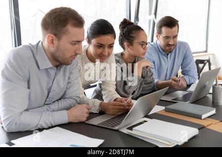 Multiracial millennial employees involved in project development, working in groups. Stock Photo