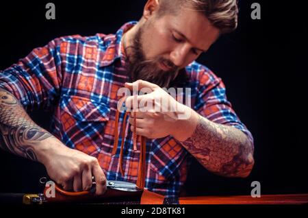 Professional Leather Worker makes quality products at the workshop Stock Photo