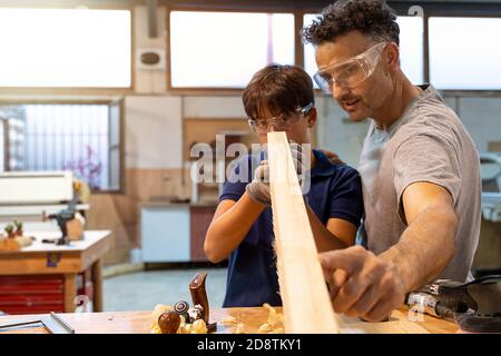 Father teaching son how to work with wood in a carpentry. Selective focus Stock Photo