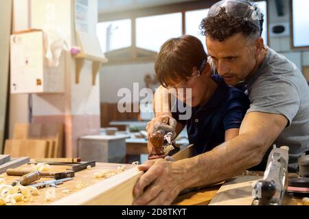 Father teaching son how to work with wood in a carpentry. Selective focus Stock Photo