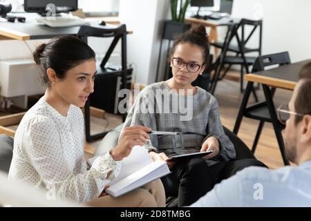Focused young diverse business people listening to female trainer. Stock Photo