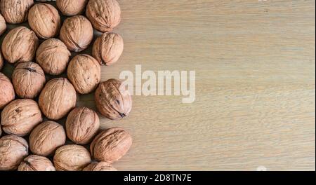 Border of whole walnuts on wooden background. Stock Photo