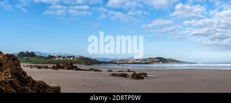 A sandy beach panorama landscape with seaside village in the hills behind Stock Photo