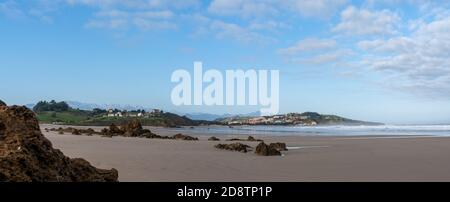 A sandy beach panorama landscape with seaside village in the hills behind Stock Photo