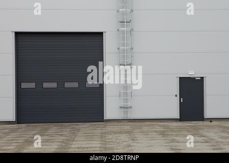 Rolling gate or roller shutter used for factory, warehouse or hangar. Metal-panel industrial building with a folding gate. Urban and construction conc Stock Photo