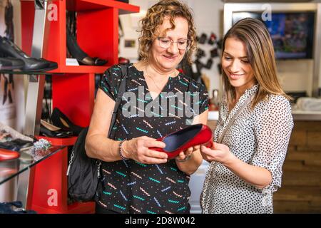 New shoes. Shopping addicted mother and daughter looking for new shoes in new showroom Stock Photo