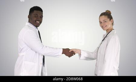 Doctors shaking hands and posing to camera on gradient backgroun Stock Photo