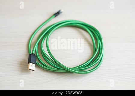 Coiled usb cable on wooden table at bright light closeup Stock Photo