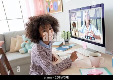 African kid girl looking at camera during online class with teacher, children. Stock Photo