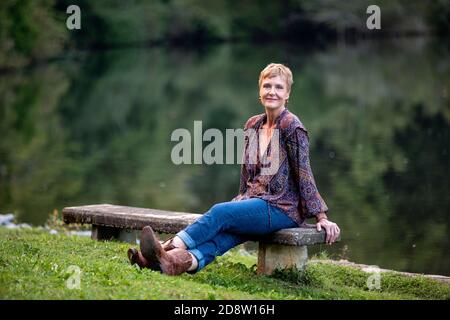 Woman sitting by lake looking at camera - Brevard, North Carolina, USA Stock Photo