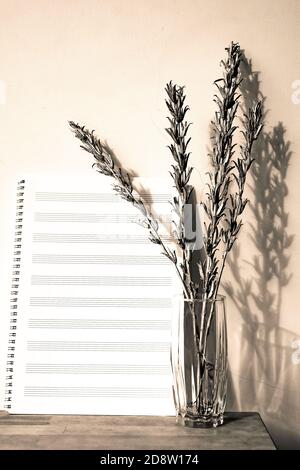 Silver grass stems in vase and music sheets on wooden table Stock Photo