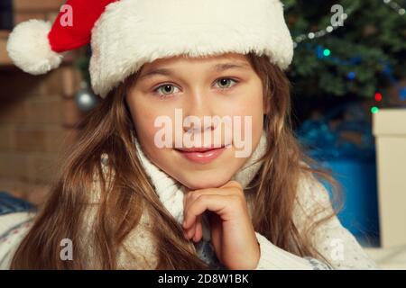 Cute teenage girl in santa hat near Christmas tree. xmas kid Stock Photo