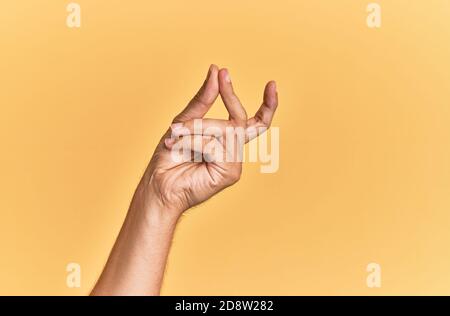 Arm and hand of caucasian man over yellow isolated background snapping fingers for success, easy and click symbol gesture with hand Stock Photo