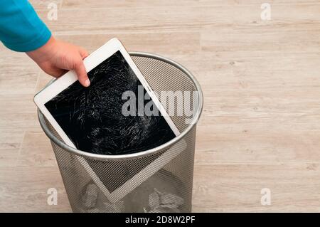Boy throws it in the trash modern tablet with highly broken screen Stock Photo