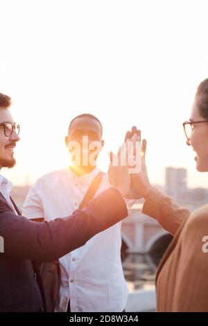 Cheerful colleagues giving each other high five while standing by riverside Stock Photo