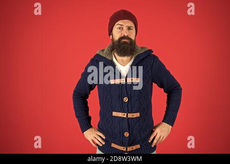 Winter season menswear. Personal stylist. Warm and comfortable. Fashion menswear shop. Masculine clothes concept. Winter menswear. Clothes design. Man bearded warm jumper and hat red background. Stock Photo