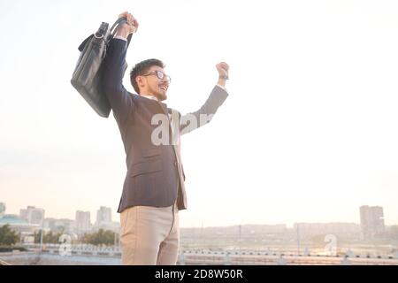 Young excited businessman with black leather handbag expressing triumph Stock Photo