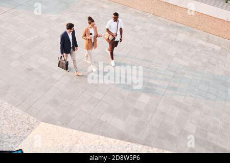 Three young intercultural business partners having discussion on the move Stock Photo