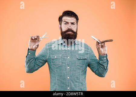 Personal stylist. Vintage barber. Bearded man hold razor and scissors. Retro barbershop. Hipster with old tools. Designing haircut. Fresh hairstyle. Barbershop concept. Care for men. Barbershop salon. Stock Photo