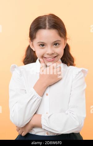 She is planning a prank. Girl school uniform smiling cunning face yellow background. Girl happy back to school. Child ready back to school end continue fun. Schoolgirl formal outfit looks cute. Stock Photo