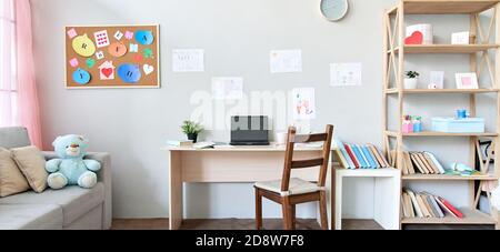 Child room interior space with table, couch, books and laptop on table at home. Stock Photo
