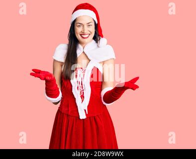 Young beautiful caucasian woman wearing santa claus costume smiling cheerful with open arms as friendly welcome, positive and confident greetings Stock Photo