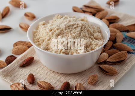 Almond nuts and almond flour in a plate are on a white table Stock Photo