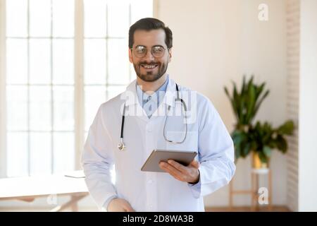 Portrait of happy confident young male doctor with tablet pc Stock Photo