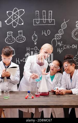 Group of clever students of secondary school watching chemical experiment Stock Photo