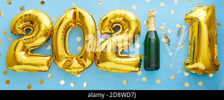 2021 golden balloon text on blue background bottle of champagne and glasses with confetti. Happy New year eve invitation with Christmas gold foil Stock Photo