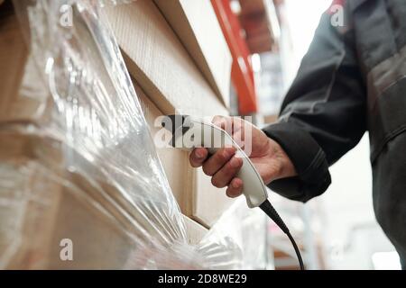 Hand of male manager of warehouse scanning qr codes on packed stacks of boxes Stock Photo