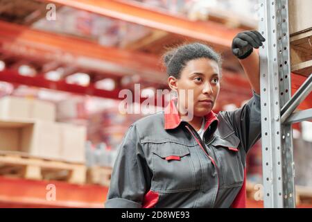 Middle aged mixed-race female worker in gloves and grey uniform having rest Stock Photo