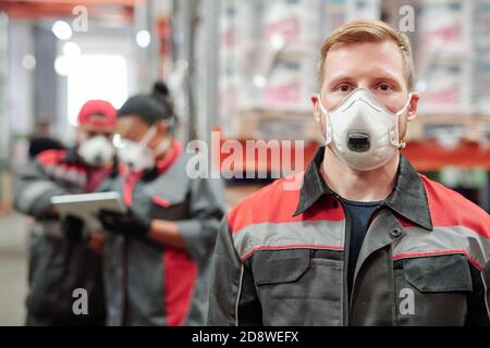 Confident young man in workwear and protective respirator looking at you Stock Photo