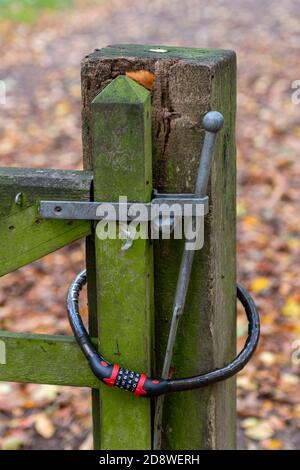 a spring gate latch with a combination padlock for security and green mould and algae on the wood of the gate and post. Stock Photo