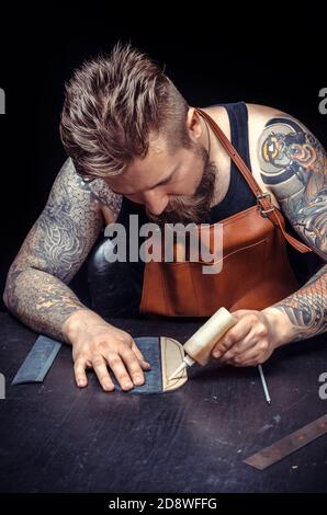Artisan working with leather working with leatherwork at the leather shop Stock Photo
