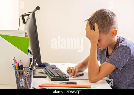 Kid with computer doing homework at home. Learning difficulties, online learning, education concept Stock Photo