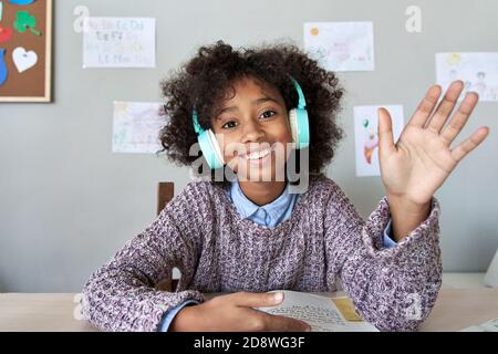 Happy african kid girl waving hand video calling remote learning, headshot. Stock Photo
