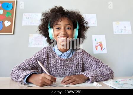 Happy african kid girl looking at web cam remote learning online, headshot. Stock Photo