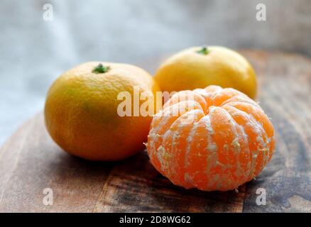 Тangerines on a wooden background with green leaves. Bright orange citrus fruits Stock Photo