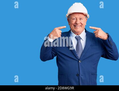 Senior handsome grey-haired man wearing suit and architect hardhat smiling cheerful showing and pointing with fingers teeth and mouth. dental health c Stock Photo