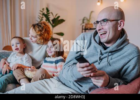 Entertained father watching television together with his wife and children