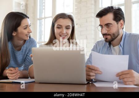 Group of three successful young businesspeople using laptop developing startup Stock Photo