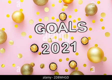 2021 Goals lettering on pink background with fastive christmas decor, golden confetti, balls. New year eve 2021 goals. Stock Photo