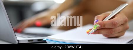 Female hands near the laptop write in a notebook Stock Photo