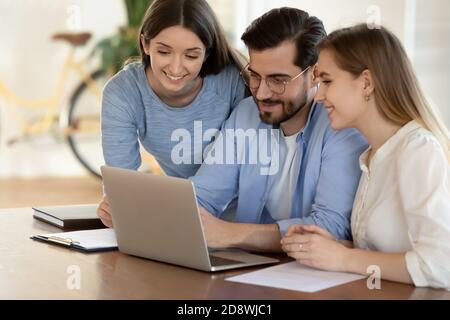 Happy young employee sharing vacation photos with two female colleagues Stock Photo