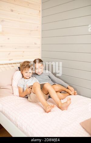 Cute little blond siblings with touchscreen laughing while watching online video Stock Photo