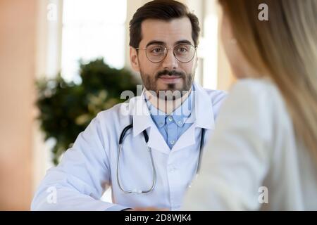Friendly attentive male doctor listening to complaints of female patient Stock Photo