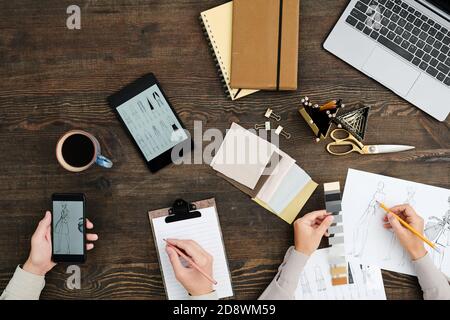 Flatlay of hands of male and female creative fashion designers working by table Stock Photo