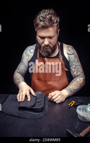 Skinner demostrating leather cutting process in leather shop Stock Photo