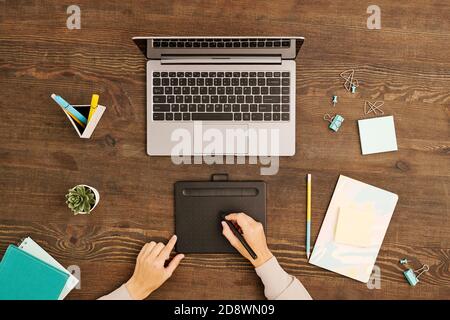 Hands of contemporary designer using stylus and graphic tablet while drawing Stock Photo